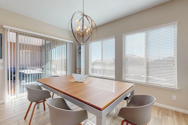 dining area with light wood finished floors, baseboards, a textured ceiling, and an inviting chandelier