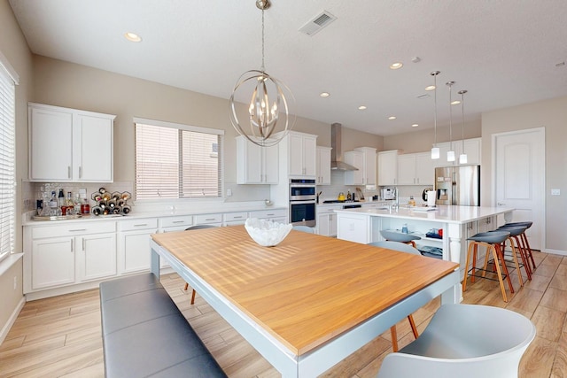 kitchen featuring visible vents, white cabinetry, stainless steel appliances, light countertops, and a chandelier