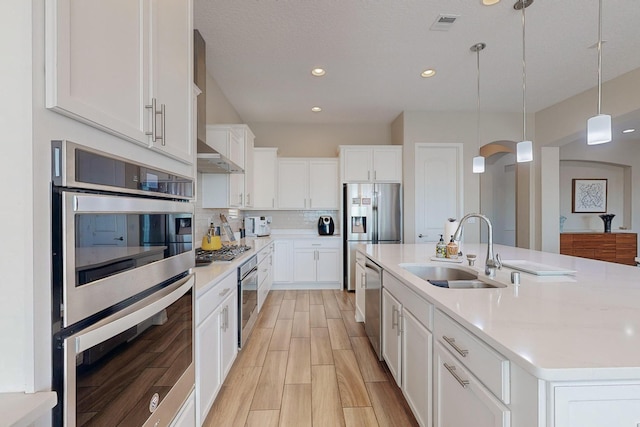 9020 Retablo Rd NW, Albuquerque, NM 87120 - kitchen featuring tasteful backsplash, a sink, light wood finished floors, hanging light fixtures, and stainless steel appliances