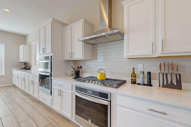 9020 Retablo Rd NW, Albuquerque, NM 87120 - kitchen with decorative backsplash, wall chimney exhaust hood, appliances with stainless steel finishes, and white cabinetry