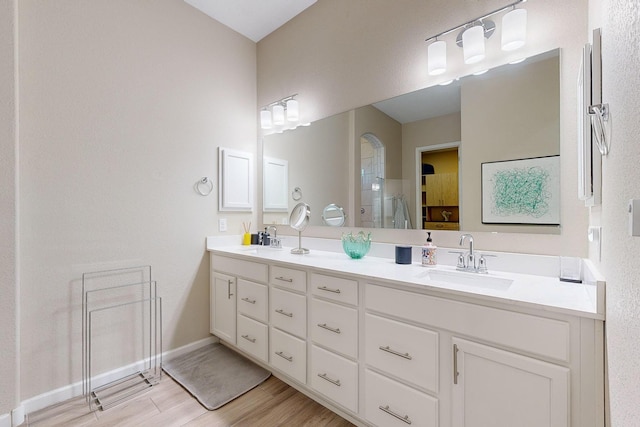 full bathroom with double vanity, an enclosed shower, wood finished floors, and a sink