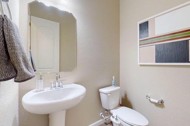 bathroom with toilet, baseboards, and a sink