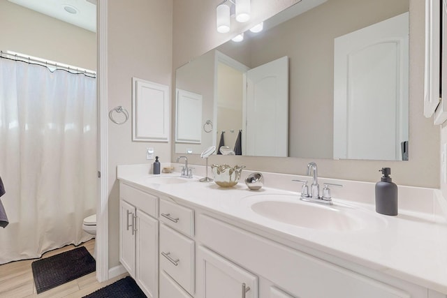 9020 Retablo Rd NW, Albuquerque, NM 87120 - bathroom with double vanity, toilet, a sink, and wood finished floors