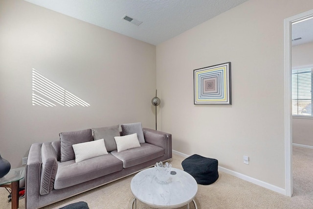 living area with carpet flooring, baseboards, visible vents, and a textured ceiling