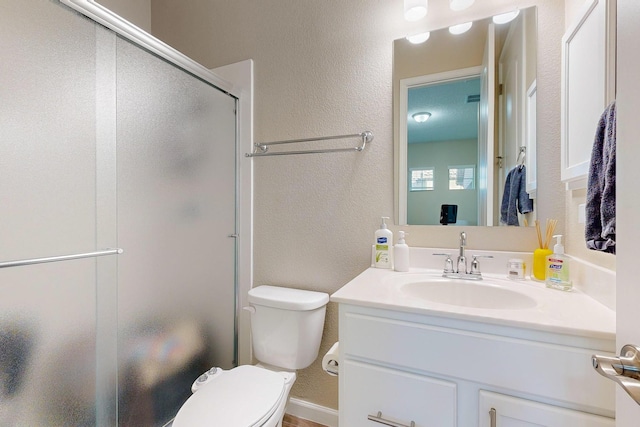 full bathroom with vanity, toilet, a textured wall, and a stall shower