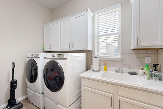 laundry area with washer and dryer, cabinet space, baseboards, and a sink