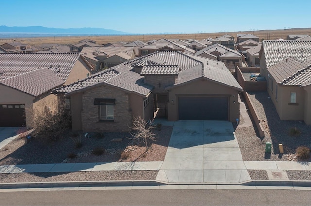 view of front of house with a residential view, an attached garage, a tile roof, and concrete driveway