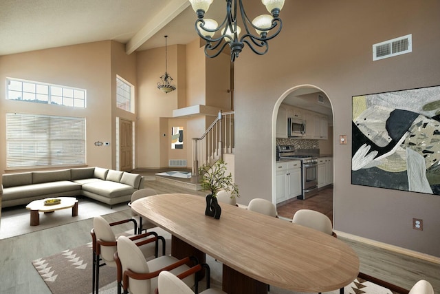 dining space featuring visible vents, arched walkways, stairway, wood finished floors, and an inviting chandelier