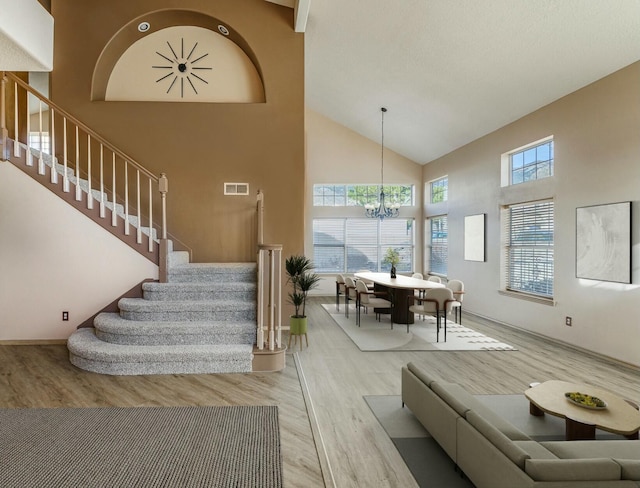 stairway featuring a towering ceiling, an inviting chandelier, visible vents, and wood finished floors