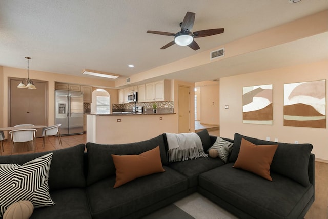 living area with arched walkways, light tile patterned flooring, recessed lighting, visible vents, and a ceiling fan