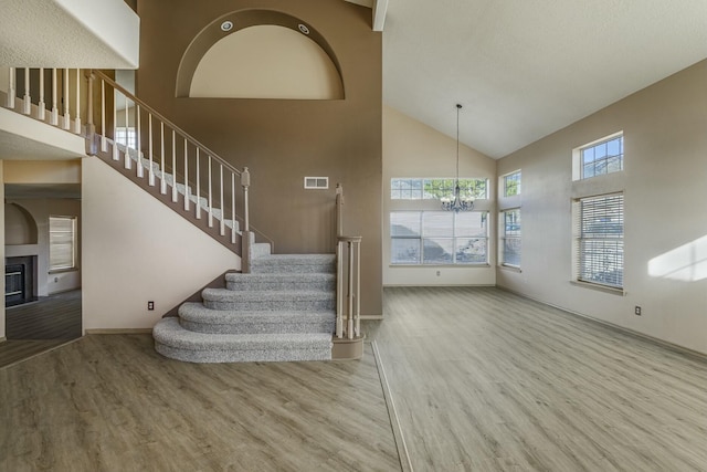 interior space with a chandelier, a glass covered fireplace, a high ceiling, and wood finished floors