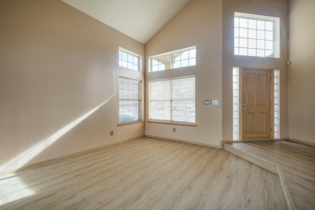 entryway with high vaulted ceiling, baseboards, and wood finished floors