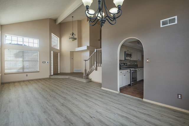 unfurnished living room featuring an inviting chandelier, stairs, visible vents, and arched walkways