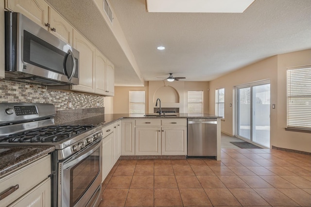 kitchen featuring stainless steel appliances, visible vents, backsplash, a sink, and a peninsula