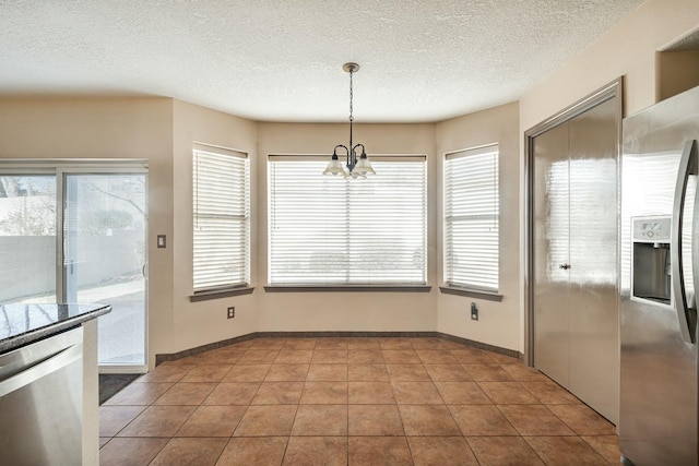 unfurnished dining area with a healthy amount of sunlight, a chandelier, a textured ceiling, and tile patterned floors