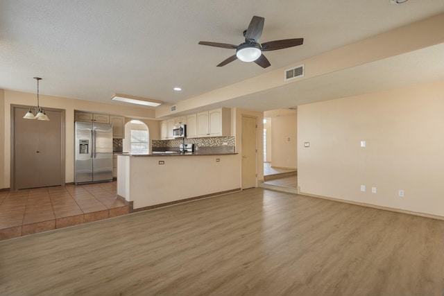 kitchen featuring visible vents, open floor plan, appliances with stainless steel finishes, tasteful backsplash, and dark countertops