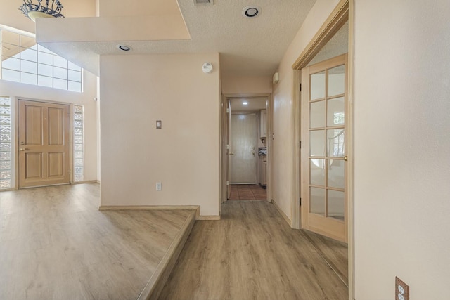 entrance foyer with a textured ceiling, light wood-type flooring, and baseboards