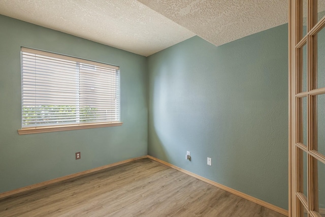 spare room featuring a textured ceiling, baseboards, and wood finished floors