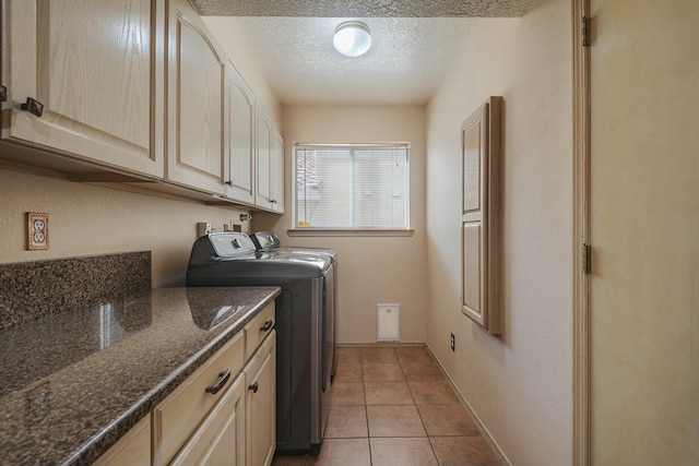 laundry room with a textured ceiling, separate washer and dryer, light tile patterned flooring, and cabinet space