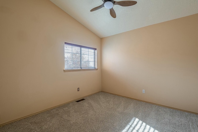 carpeted spare room with lofted ceiling, a textured ceiling, visible vents, and a ceiling fan