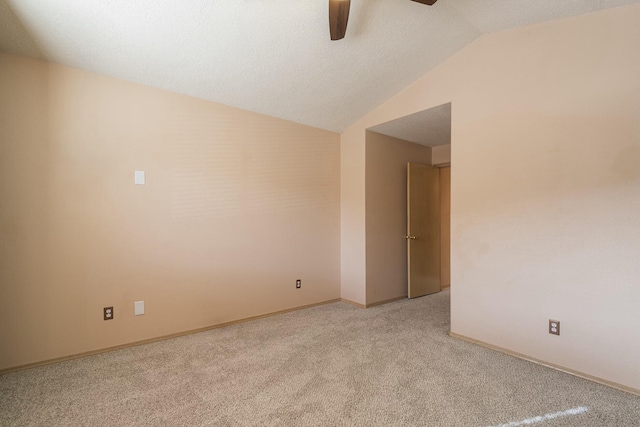 empty room with lofted ceiling, light colored carpet, ceiling fan, and baseboards