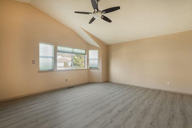 unfurnished room featuring a ceiling fan, lofted ceiling, baseboards, and wood finished floors