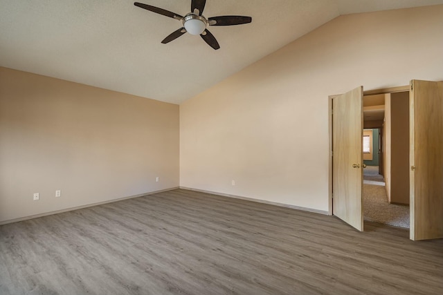 empty room featuring lofted ceiling, ceiling fan, baseboards, and wood finished floors