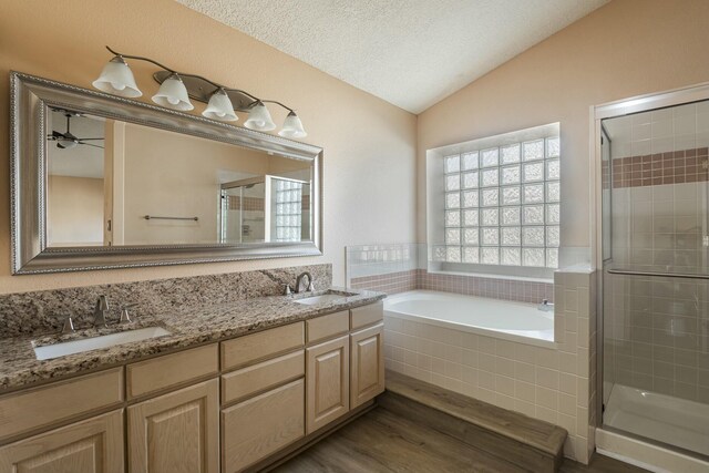 full bath featuring vaulted ceiling, a garden tub, a sink, and a shower stall