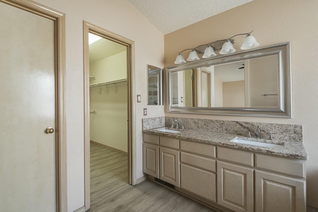 bathroom featuring double vanity, a sink, a textured ceiling, and wood finished floors