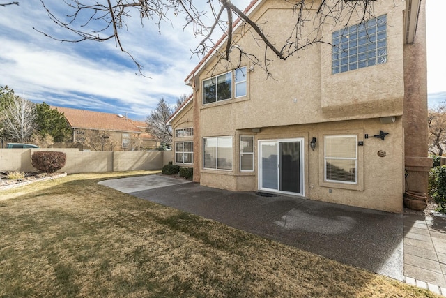 rear view of property with a yard, a patio area, fence, and stucco siding