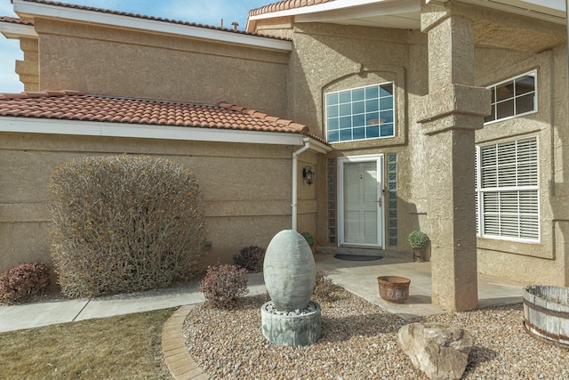 property entrance featuring a patio, a tiled roof, and stucco siding