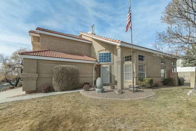 back of house featuring stucco siding, a tile roof, fence, and a yard