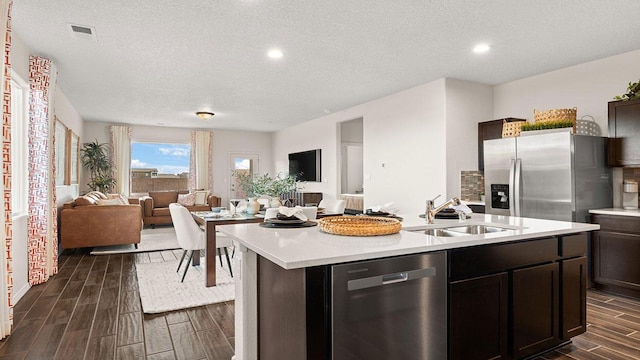 kitchen featuring light countertops, a sink, open floor plan, wood finish floors, and stainless steel appliances