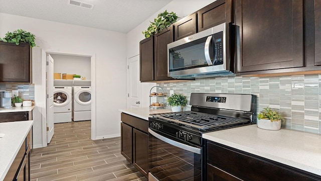 kitchen featuring light countertops, visible vents, stainless steel appliances, dark brown cabinets, and washing machine and dryer
