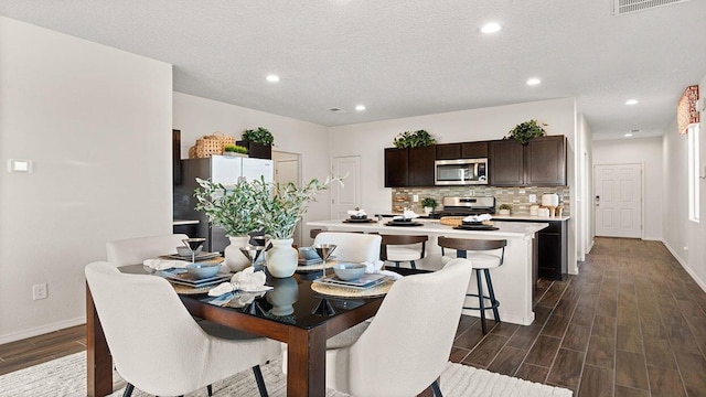 dining room featuring baseboards, dark wood-style flooring, a textured ceiling, and recessed lighting