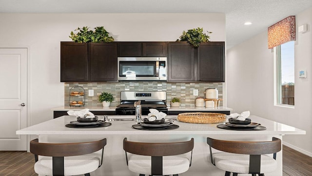 kitchen featuring decorative backsplash, light countertops, stainless steel appliances, and a breakfast bar area