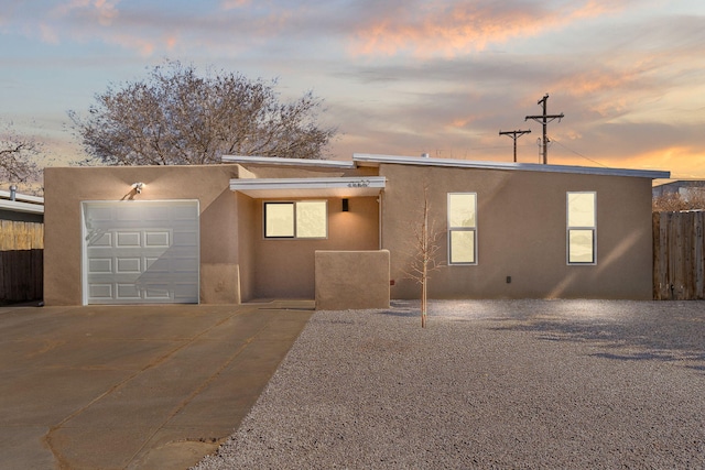 view of front of property with driveway, fence, an attached garage, and stucco siding