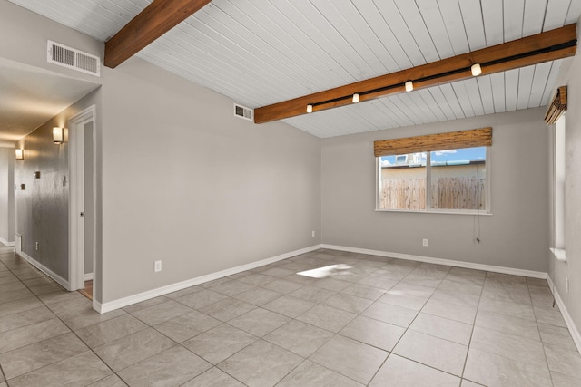 empty room featuring beamed ceiling, light tile patterned flooring, visible vents, and baseboards