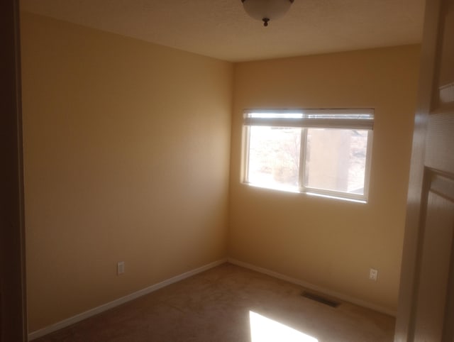 spare room featuring carpet flooring, visible vents, and baseboards