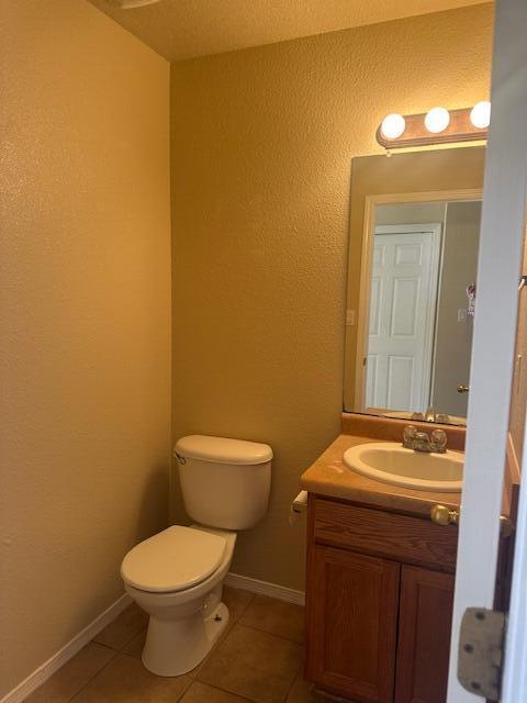 bathroom with toilet, tile patterned flooring, baseboards, and vanity