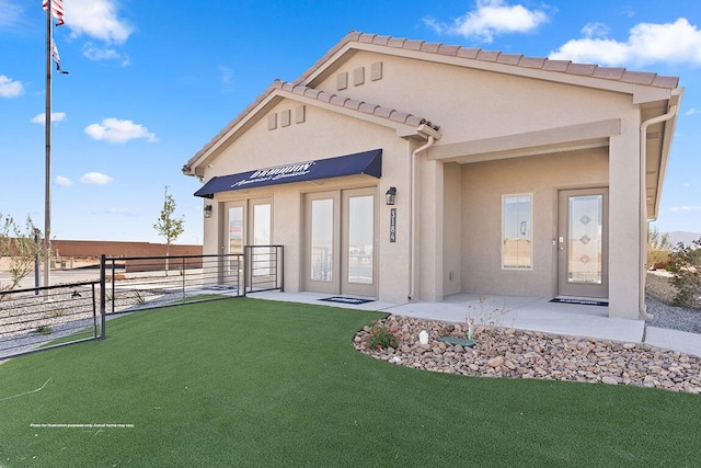 exterior space featuring a tiled roof, fence, a lawn, and stucco siding