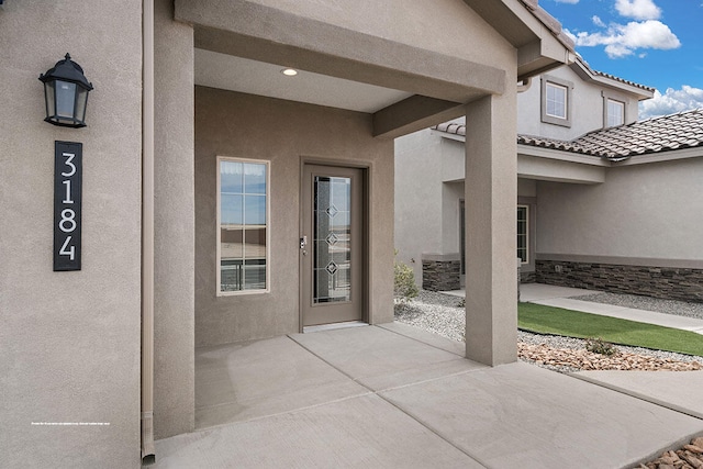 property entrance with cooling unit, a patio, a tiled roof, and stucco siding