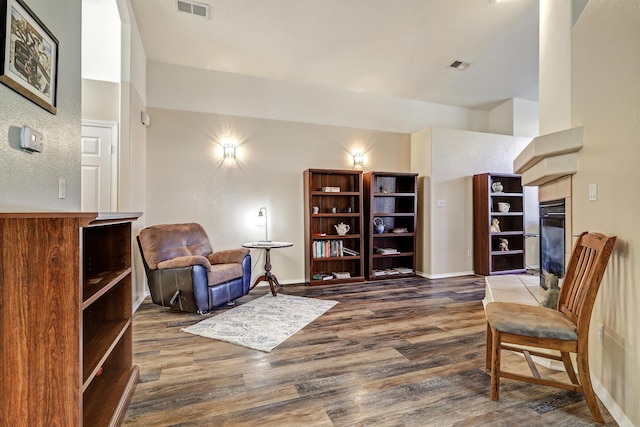 sitting room featuring baseboards, a tiled fireplace, visible vents, and wood finished floors