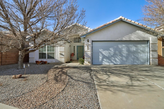 ranch-style home featuring concrete driveway, an attached garage, a tiled roof, and stucco siding