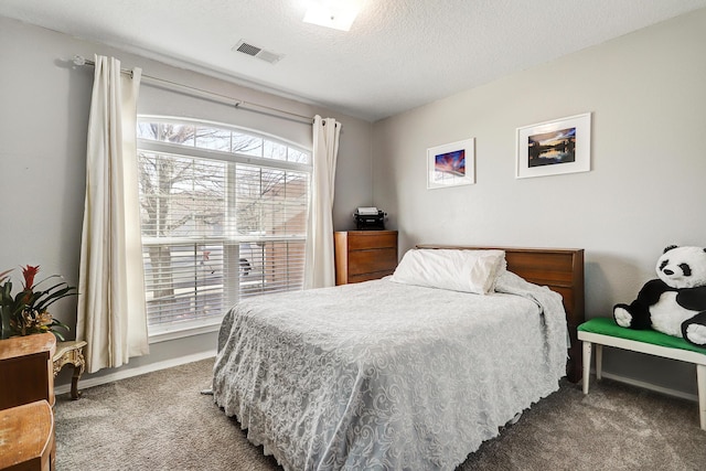 bedroom featuring baseboards, carpet flooring, visible vents, and a textured ceiling