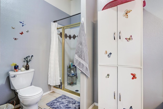 bathroom with baseboards, a stall shower, toilet, and tile patterned floors