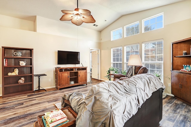 living area with baseboards, visible vents, ceiling fan, wood finished floors, and high vaulted ceiling