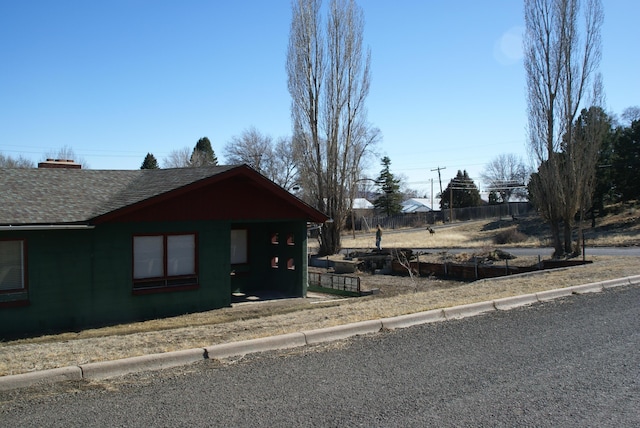 chalet / cabin featuring roof with shingles and fence