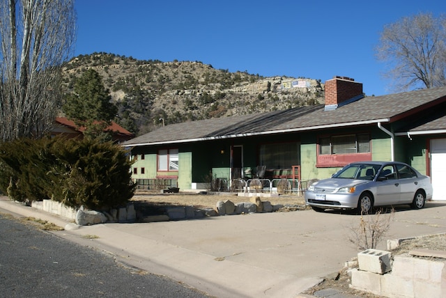 ranch-style home featuring a chimney, a mountain view, and concrete driveway