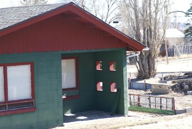 view of side of home with a shingled roof and fence